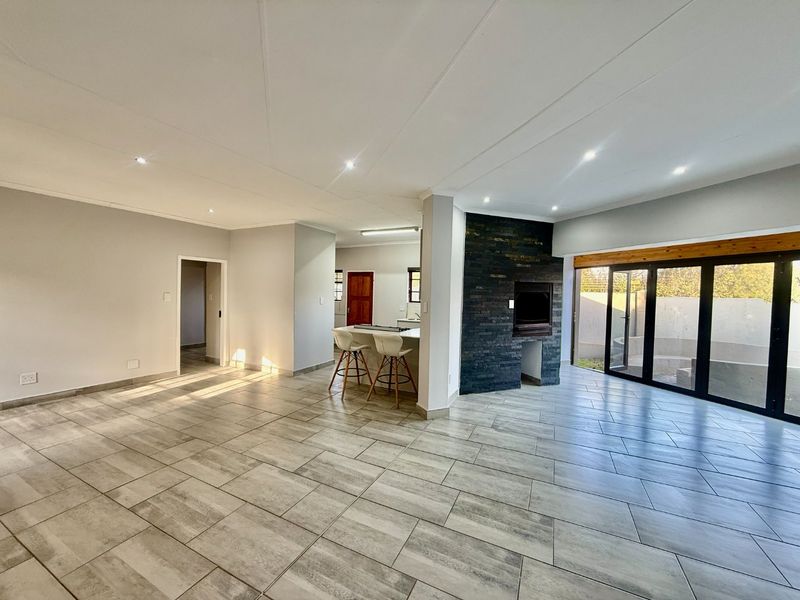 Spacious open-plan living area featuring modern tiled flooring, a striking stone-clad fireplace, and large bi-fold doors leading to the outdoor space.