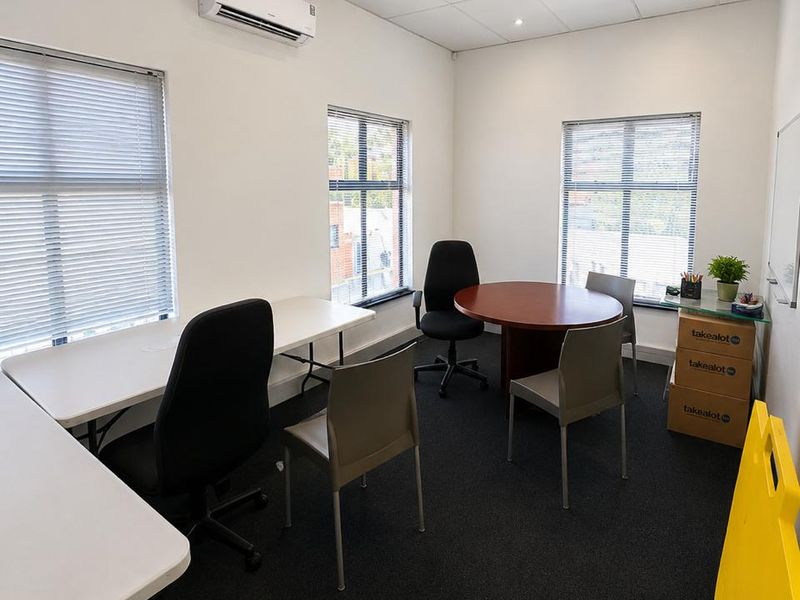 A functional commercial office space featuring a suspended ceiling, recessed lighting, split-system air conditioning, and large windows with venetian blinds.