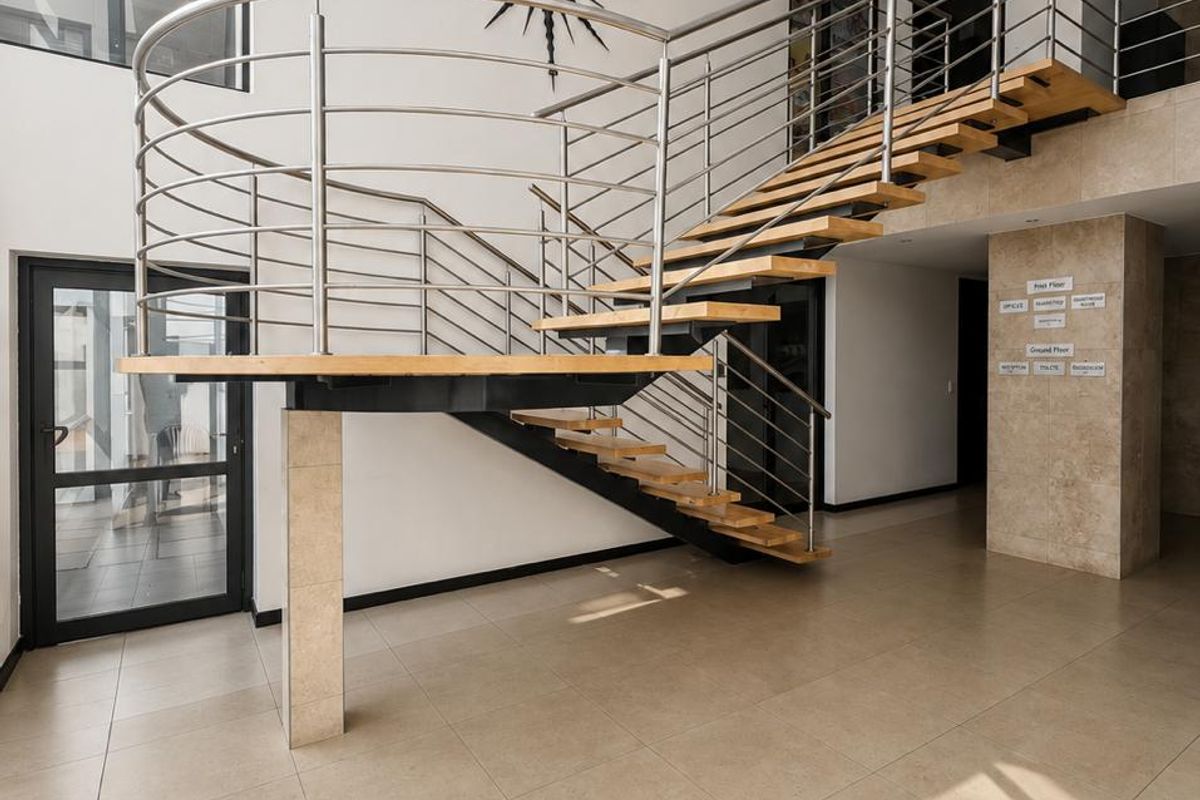 Spacious commercial entrance hall featuring a modern floating staircase with stainless steel balustrades and high-quality tiled flooring.