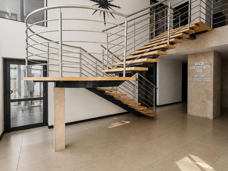 Spacious commercial entrance hall featuring a modern floating staircase with stainless steel balustrades and high-quality tiled flooring.