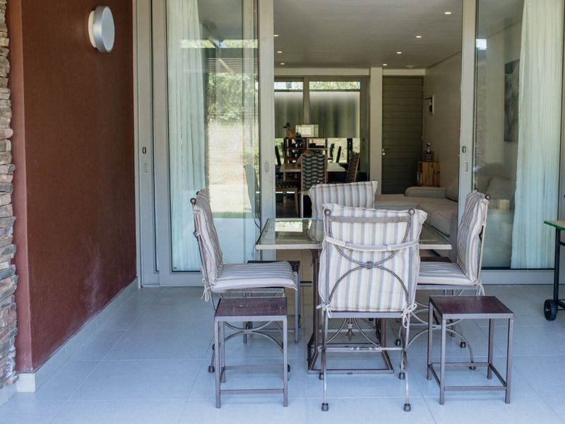 A covered patio area featuring tiled flooring, stone wall accents, and large sliding glass doors providing seamless access to the interior living space.