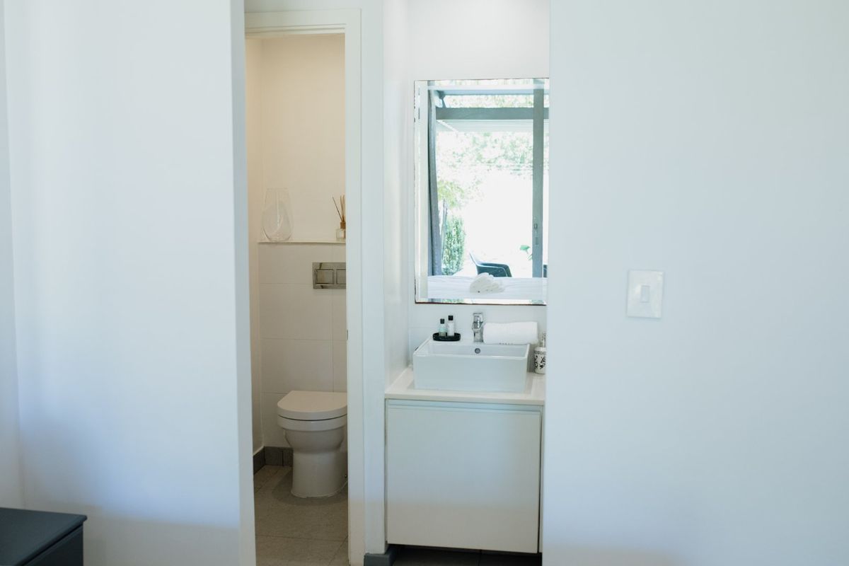 A clean, modern bathroom featuring a wall-hung toilet with a concealed cistern and a vanity unit with a vessel sink and mirror.