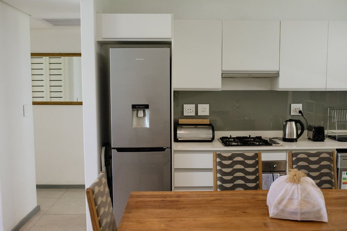 Modern kitchen featuring white cabinetry, stone countertops, a gas hob, extractor fan, and integrated glass splashback.