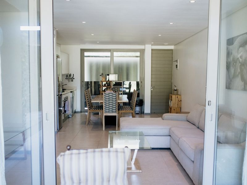 An open-plan living and dining area featuring tiled floors, recessed lighting, and a modern kitchen with integrated cabinetry and stainless steel appliances.