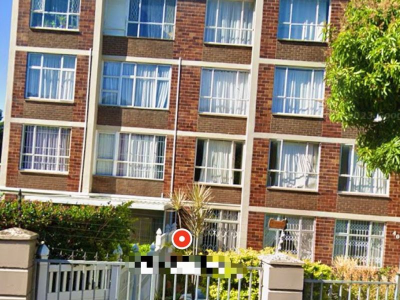 Front elevation of a multi-story brick apartment building featuring large windows and a secure gated entrance.