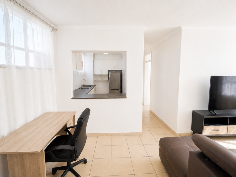 Open-plan living area featuring a functional kitchen pass-through, tiled flooring, and neutral finishes, creating a bright and connected living space.