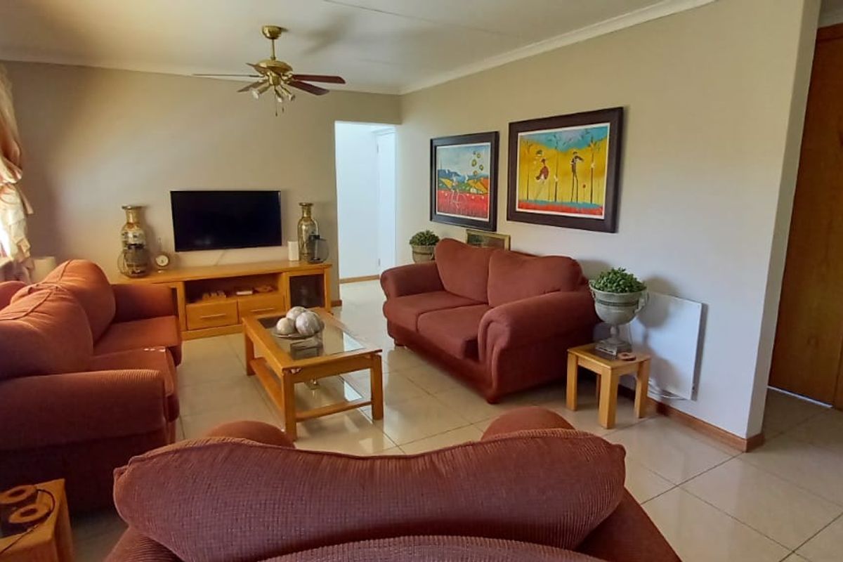 A comfortable living room featuring tiled flooring, a ceiling fan, and a built-in storage cupboard.