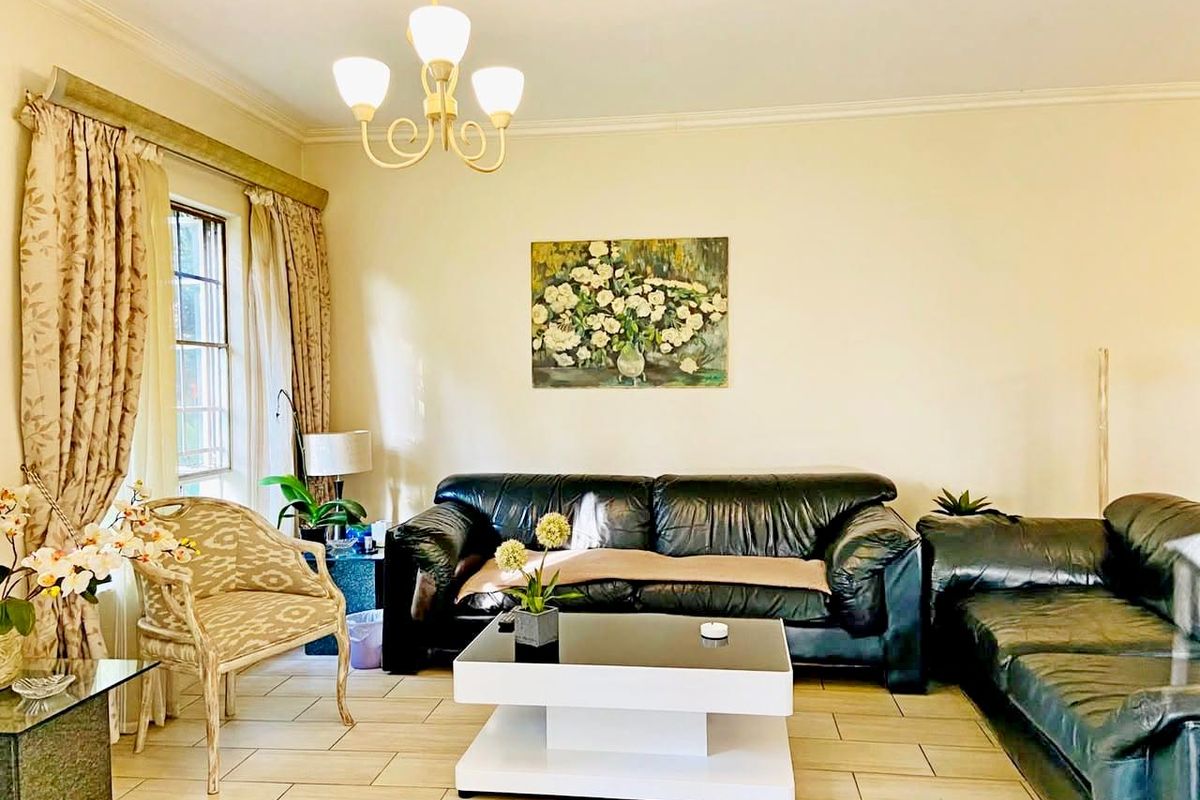 A comfortable living room featuring tiled flooring, classic ceiling cornice, and a central chandelier, providing a neutral base for interior design.