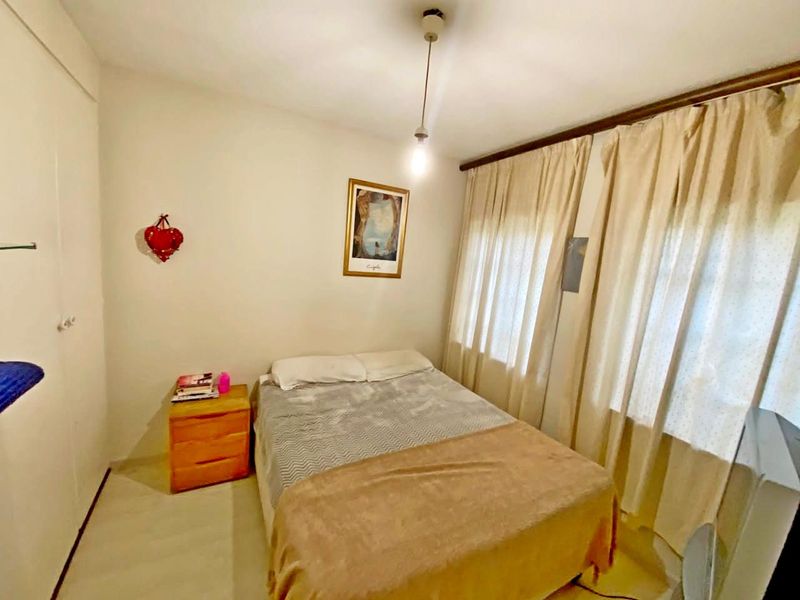 A functional bedroom featuring a built-in wardrobe and large window with curtain rod, offering a neutral space ready for personalization.