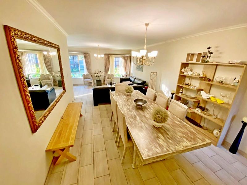 Spacious open-plan living and dining area featuring neutral tiled flooring, classic cove cornicing, and large multi-pane windows providing ample natural light.