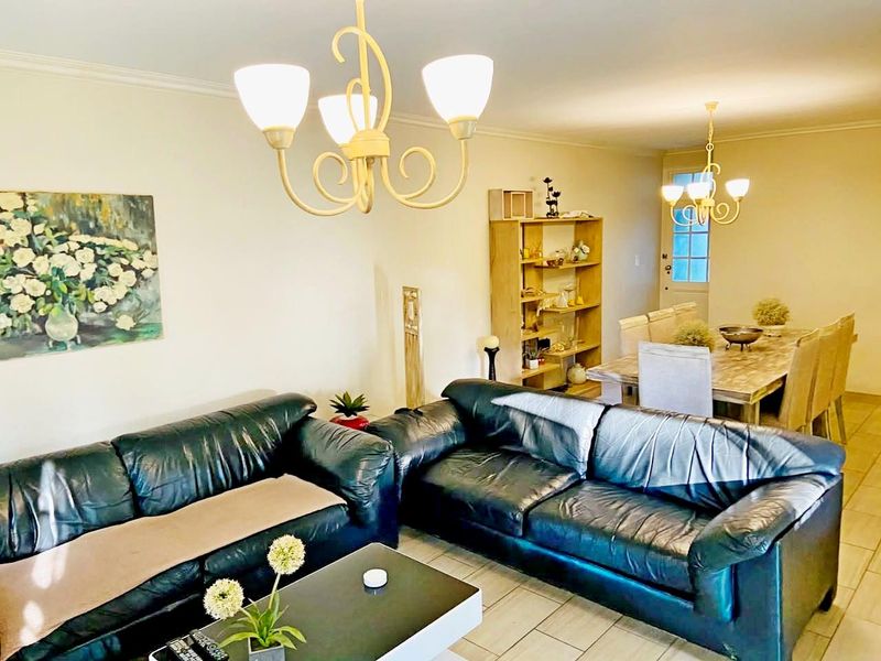 Spacious open-plan living and dining area featuring tiled flooring, decorative cornice, and classic multi-arm chandeliers, providing a versatile layout for family living.