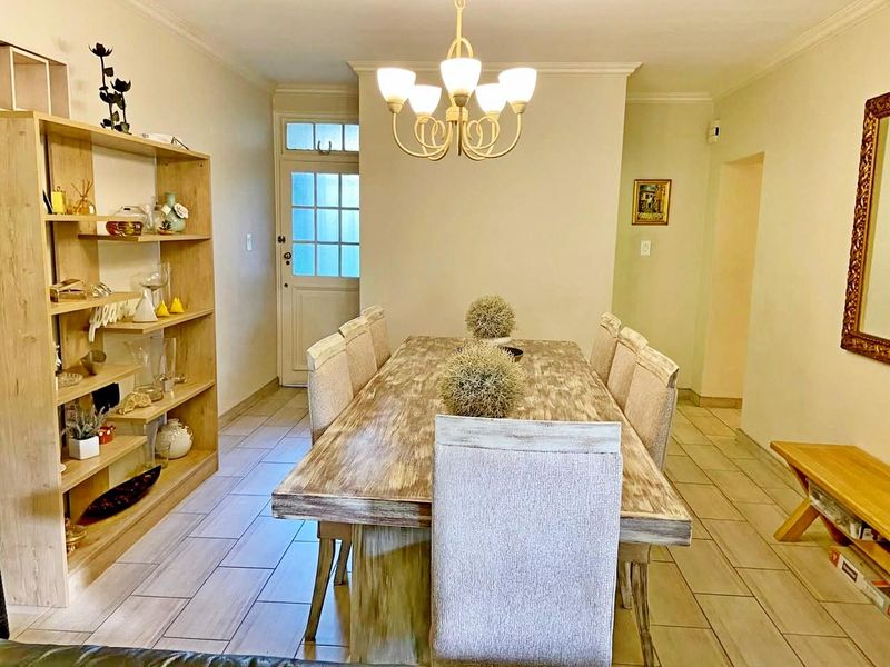 A dining room featuring tiled flooring, a classic chandelier, and a multi-pane glass entrance door, providing a functional space for family meals.
