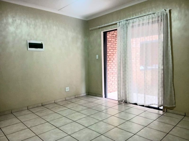 An empty living room featuring tiled flooring and a sliding glass door providing access to an outdoor area.