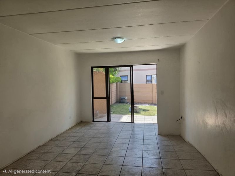An empty living room featuring tiled flooring and a sliding glass door providing direct access to the rear garden area.