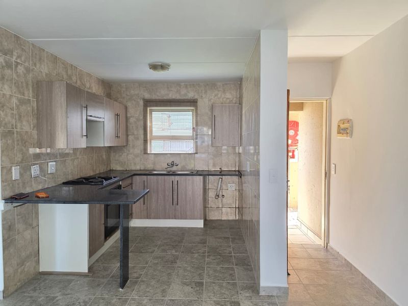 Functional kitchen featuring built-in cabinetry, laminate countertops, gas hob, under-counter oven, and tiled finishes throughout.
