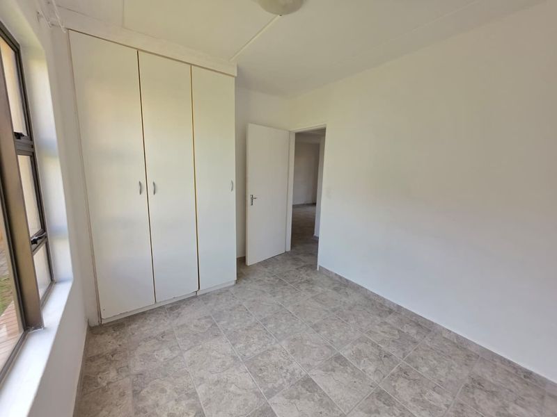 A clean, empty bedroom featuring neutral tiled flooring and built-in cupboards, offering a blank canvas for personalization.