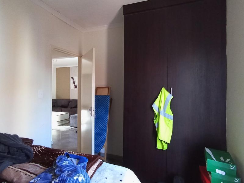 A bedroom featuring a dark wood built-in wardrobe with a view into the adjacent living area.