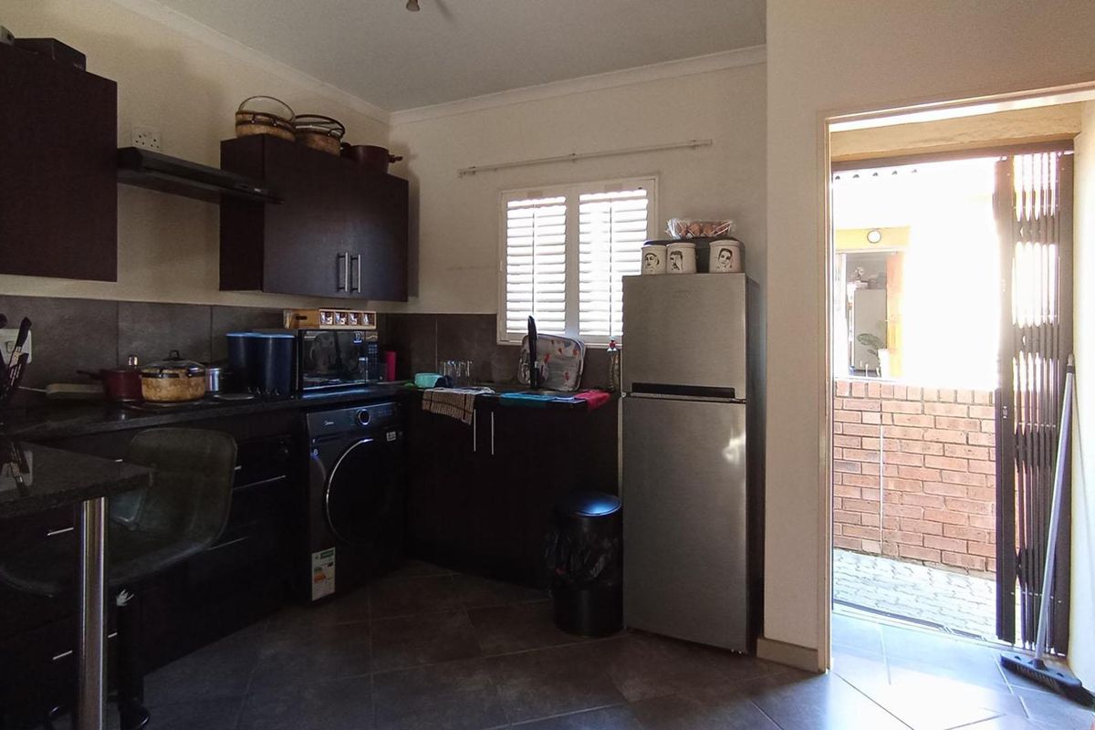 A functional kitchen featuring dark wood cabinetry, granite countertops, tiled backsplash, and built-in appliances, with direct access to an outdoor area.
