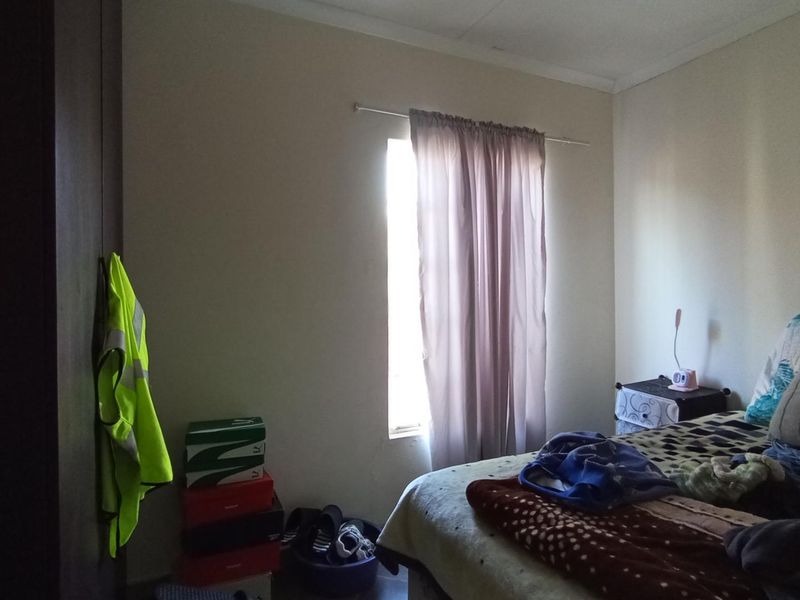 A standard bedroom featuring a built-in cupboard and a window with a curtain rod, providing a functional living space.