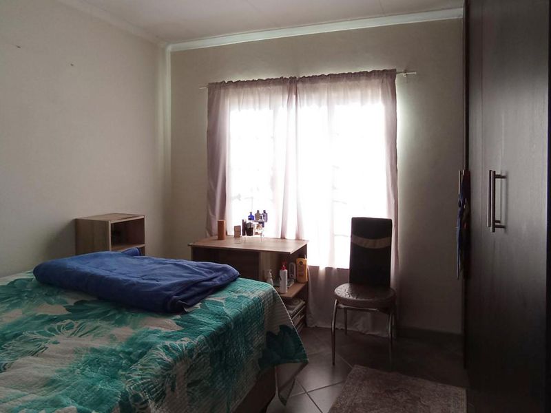 A functional bedroom featuring tiled flooring and a built-in wardrobe, offering a neutral space ready for personalization.