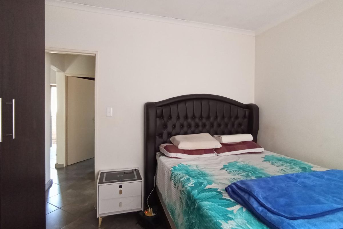 A bedroom featuring a built-in wardrobe and neutral wall finishes, providing a functional space with direct access to the hallway.