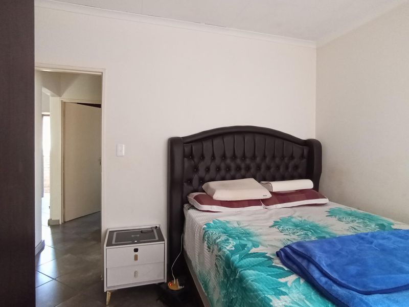 A bedroom featuring a built-in wardrobe and neutral wall finishes, providing a functional space with direct access to the hallway.