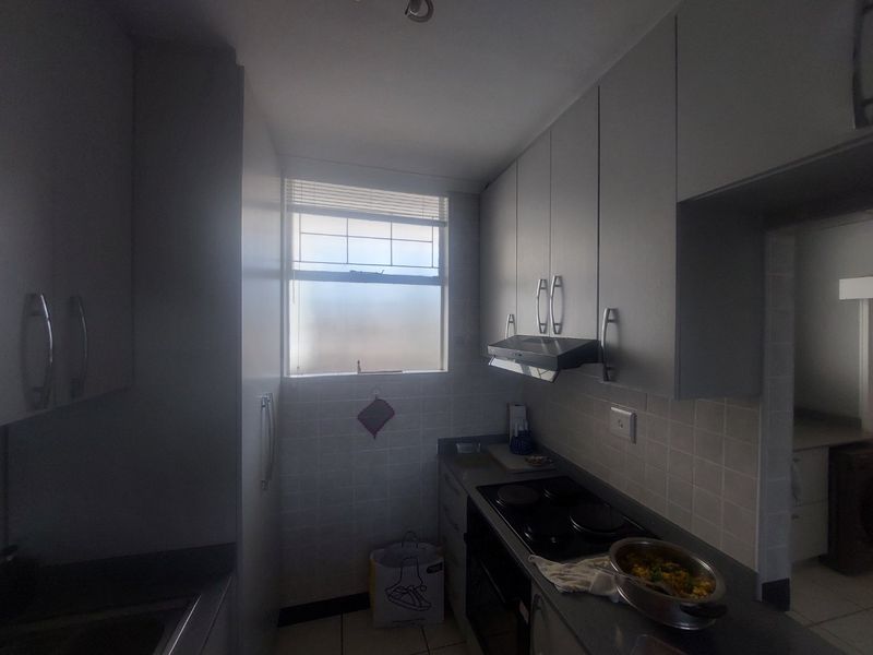 A functional kitchen featuring built-in cabinetry, an electric hob, an oven, an extractor fan, and tiled finishes.