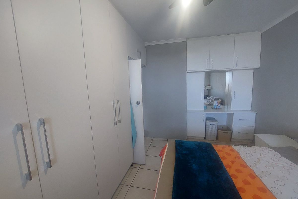 Bedroom featuring extensive built-in cupboard storage, a integrated vanity unit with overhead cabinetry, tiled flooring, and a ceiling fan.