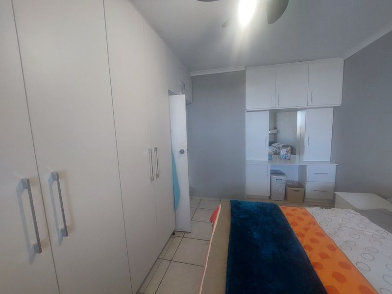 Bedroom featuring extensive built-in cupboard storage, a integrated vanity unit with overhead cabinetry, tiled flooring, and a ceiling fan.