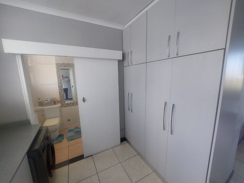 A functional laundry area featuring extensive built-in cabinetry for storage and a sliding door providing access to an adjacent bathroom.