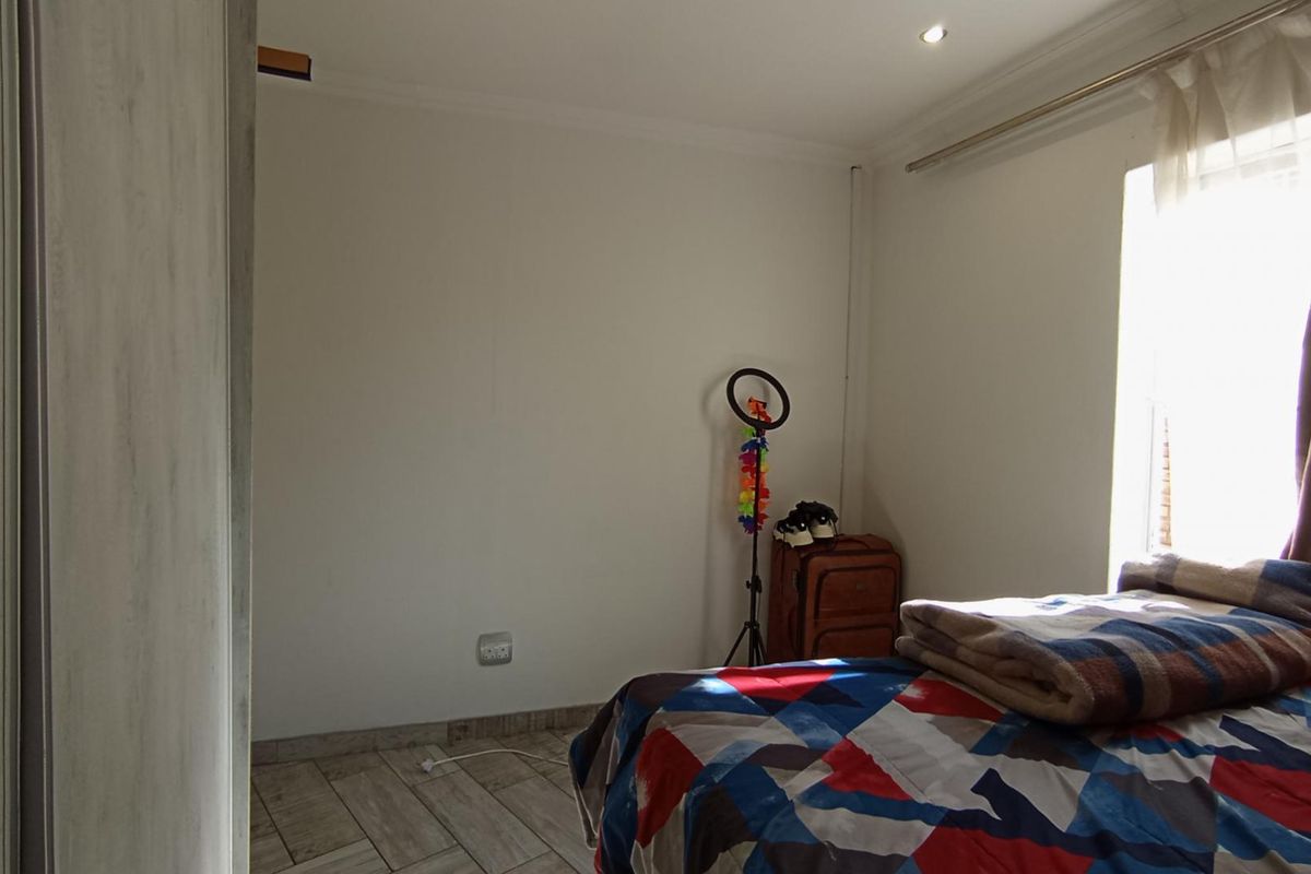 A bedroom featuring tiled flooring, recessed downlighting, and a built-in wardrobe, offering a functional space with natural light from the window.