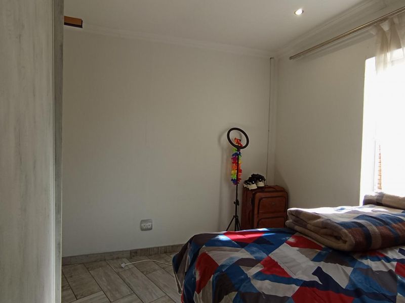 A bedroom featuring tiled flooring, recessed downlighting, and a built-in wardrobe, offering a functional space with natural light from the window.