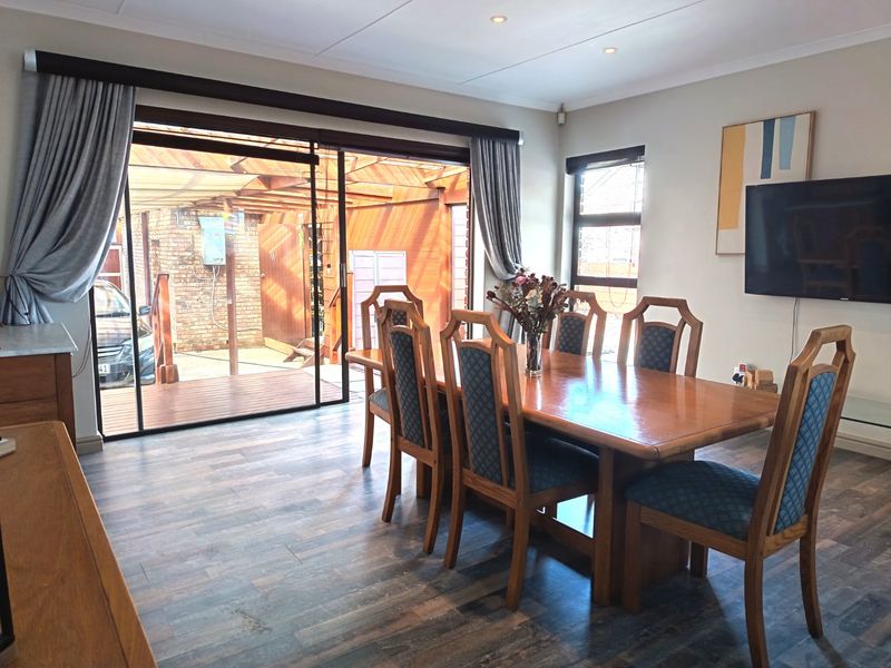 A well-lit dining room featuring laminate flooring and large sliding glass doors that provide direct access to the outdoor patio area.
