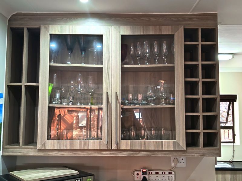 A close-up view of kitchen wall-mounted cabinetry featuring glass-fronted display doors and an integrated wine storage rack.