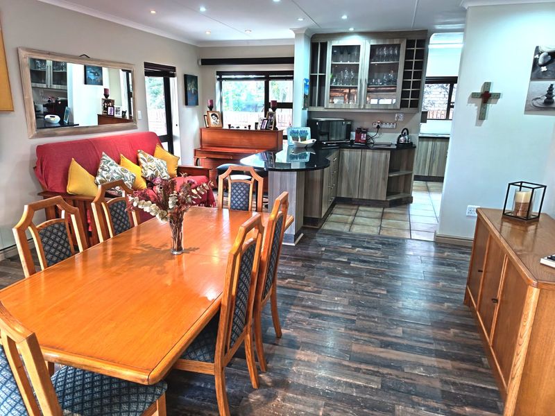 Open-plan living and dining area featuring a kitchen with built-in cabinetry, granite countertops, and a mix of tiled and wood-look laminate flooring.