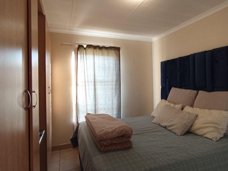 A functional bedroom featuring built-in cupboards, tiled flooring, and a coved ceiling, providing a practical and comfortable living space.