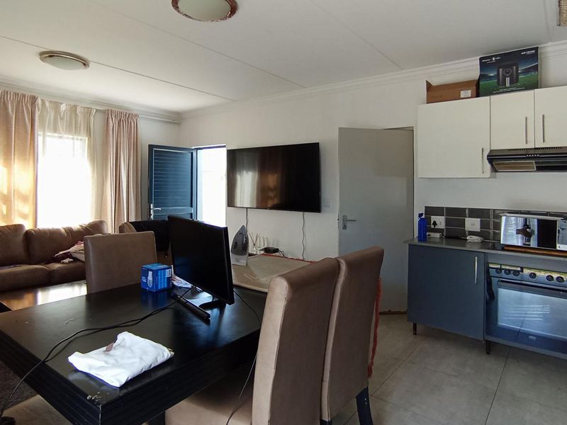 An open-plan living and kitchen area featuring tiled flooring, modern cabinetry, and a built-in oven with an extractor fan.