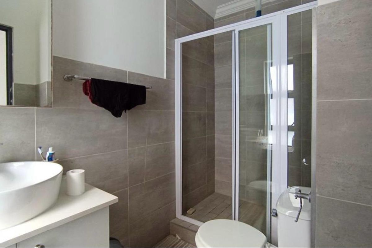 Modern bathroom featuring a vessel sink vanity, tiled walls, and a glass-enclosed shower unit.