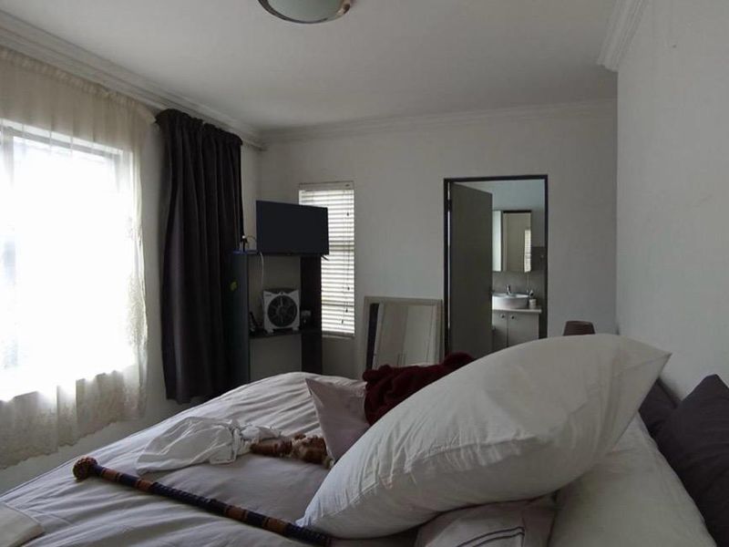 A bedroom featuring neutral walls, crown molding, and an adjoining bathroom visible through the doorway.