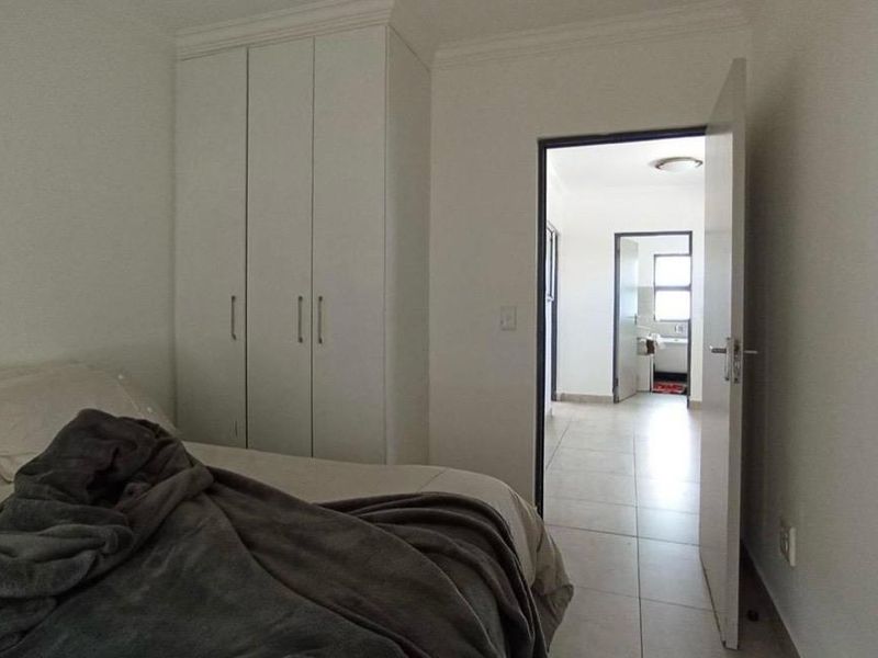 A bedroom featuring built-in cupboards and tiled flooring, with a doorway leading to an adjacent room.