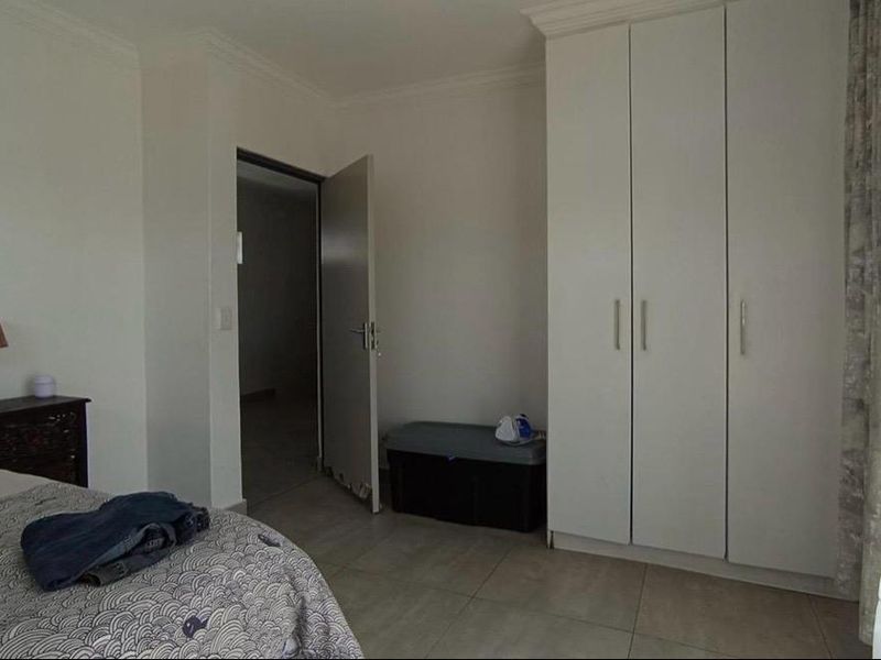 A bedroom featuring tiled flooring and a built-in white wardrobe, offering a neutral foundation for personalization.