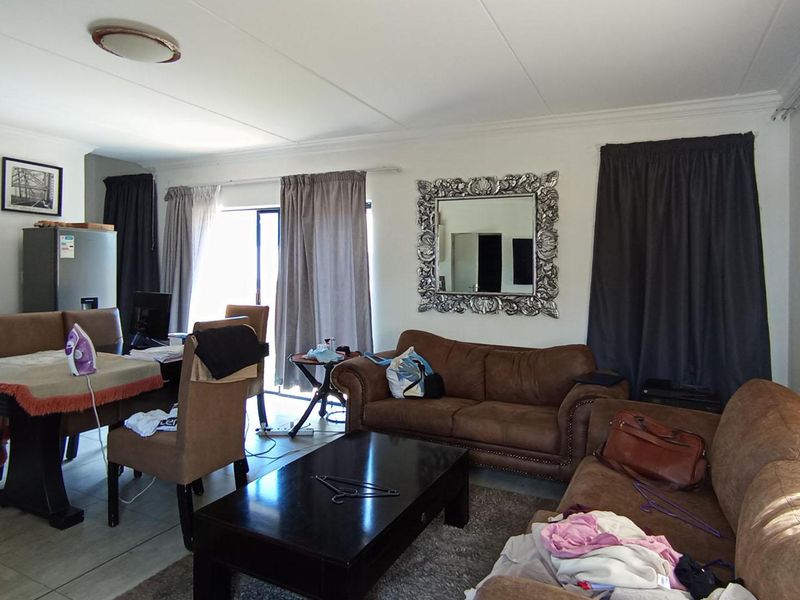 Open-plan living and dining area featuring tiled flooring and a sliding glass door providing natural light.