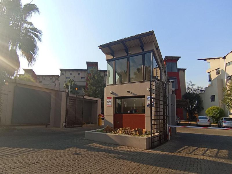 The entrance to the apartment complex features a secure guard house, boom gate access, and perimeter electric fencing.