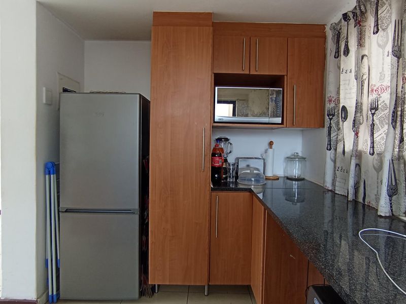 A functional kitchen area featuring wood-finish cabinetry, granite countertops, and a built-in microwave space.