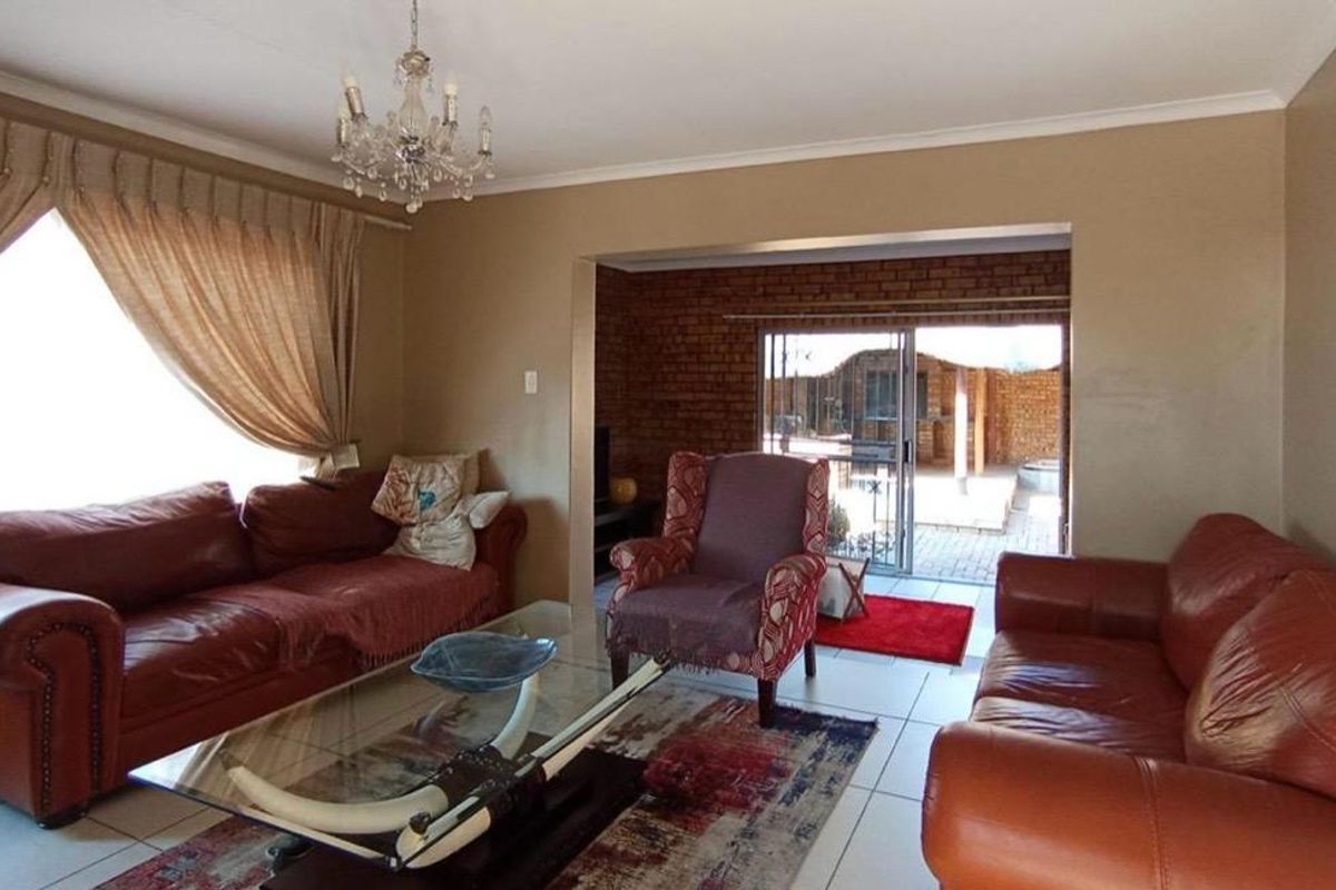 Spacious living room featuring tiled flooring, an exposed brick feature wall, and sliding glass doors providing direct access to the outdoor patio area.