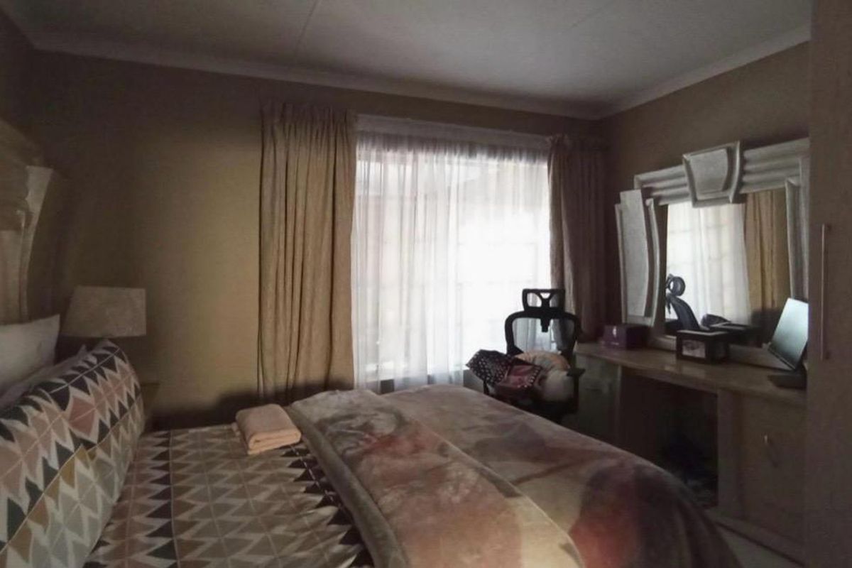 A bedroom featuring a built-in vanity unit and window with curtain rails, offering a functional space with neutral wall tones.