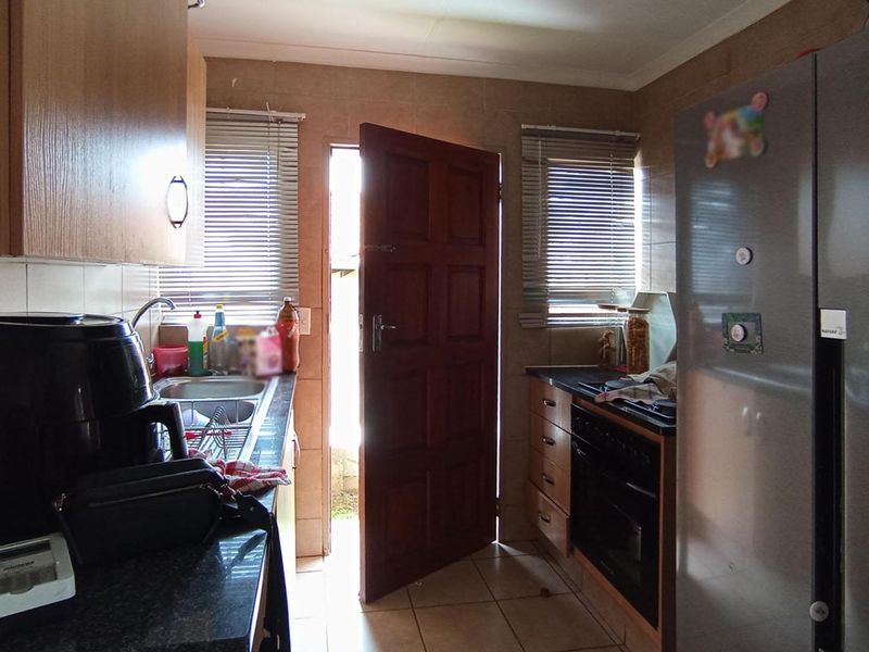 A functional kitchen featuring built-in cabinetry, laminate countertops, a stainless steel sink, and a built-in oven with tiled flooring and backsplash.