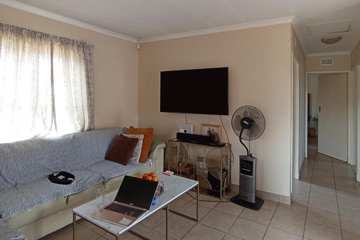A functional living room featuring tiled flooring and coved ceilings, providing a neutral base for potential interior updates.