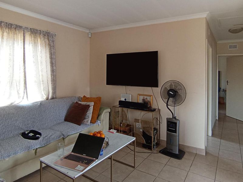 A functional living room featuring tiled flooring and coved ceilings, providing a neutral base for potential interior updates.