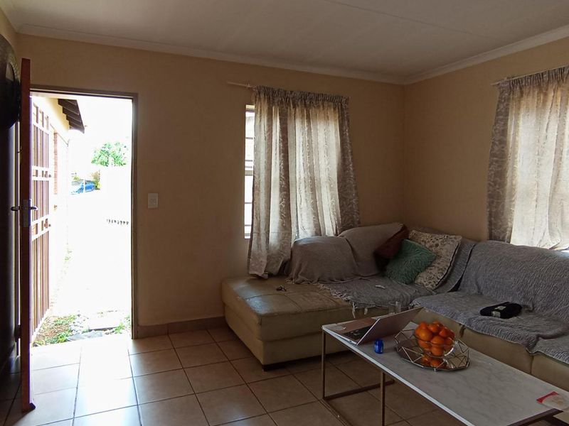 A functional living room featuring tiled flooring and direct access to the exterior through a security gate.